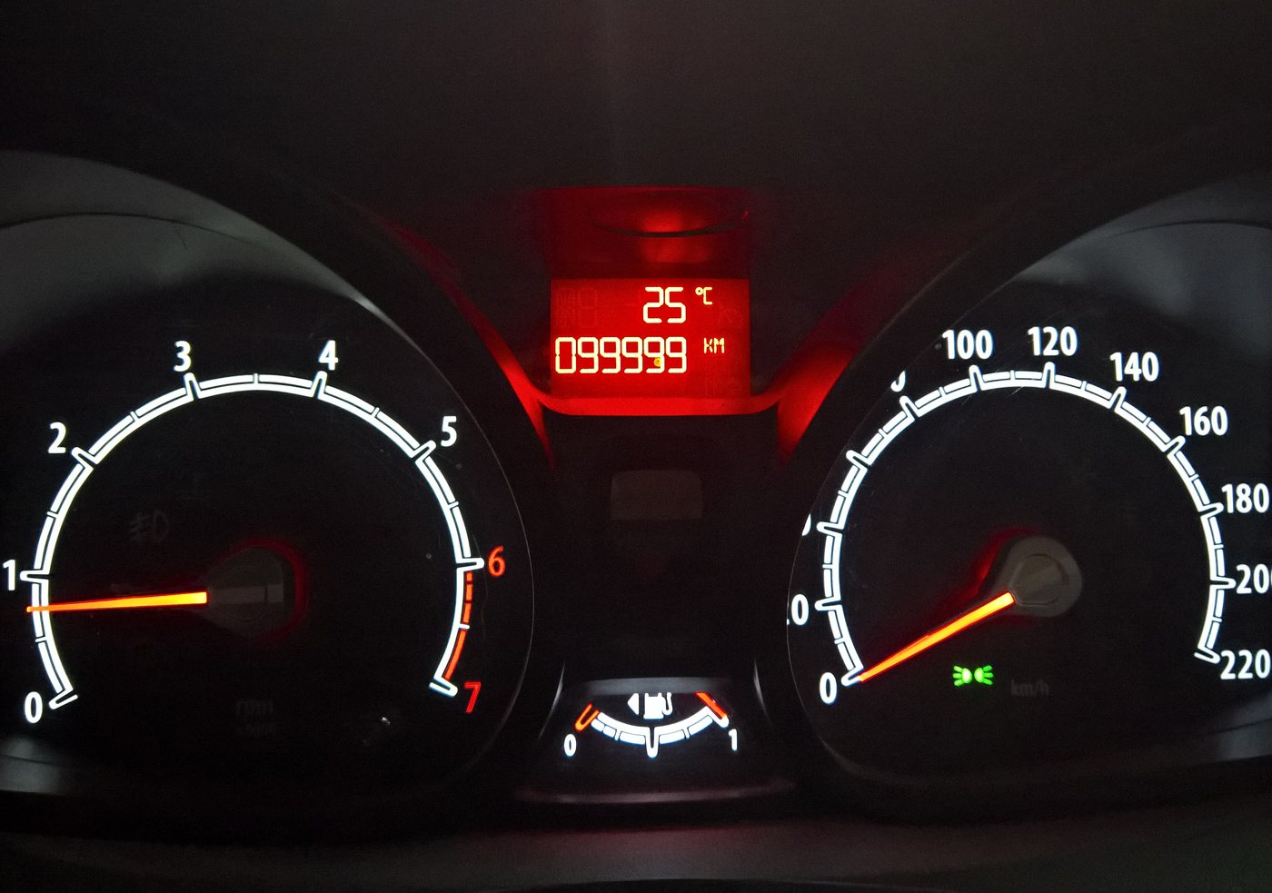 Ford Fiesta Mk7 instrument cluster lit up at night: rev counter and speedometer either side of the red centre display that fades and goes blank on these cars
