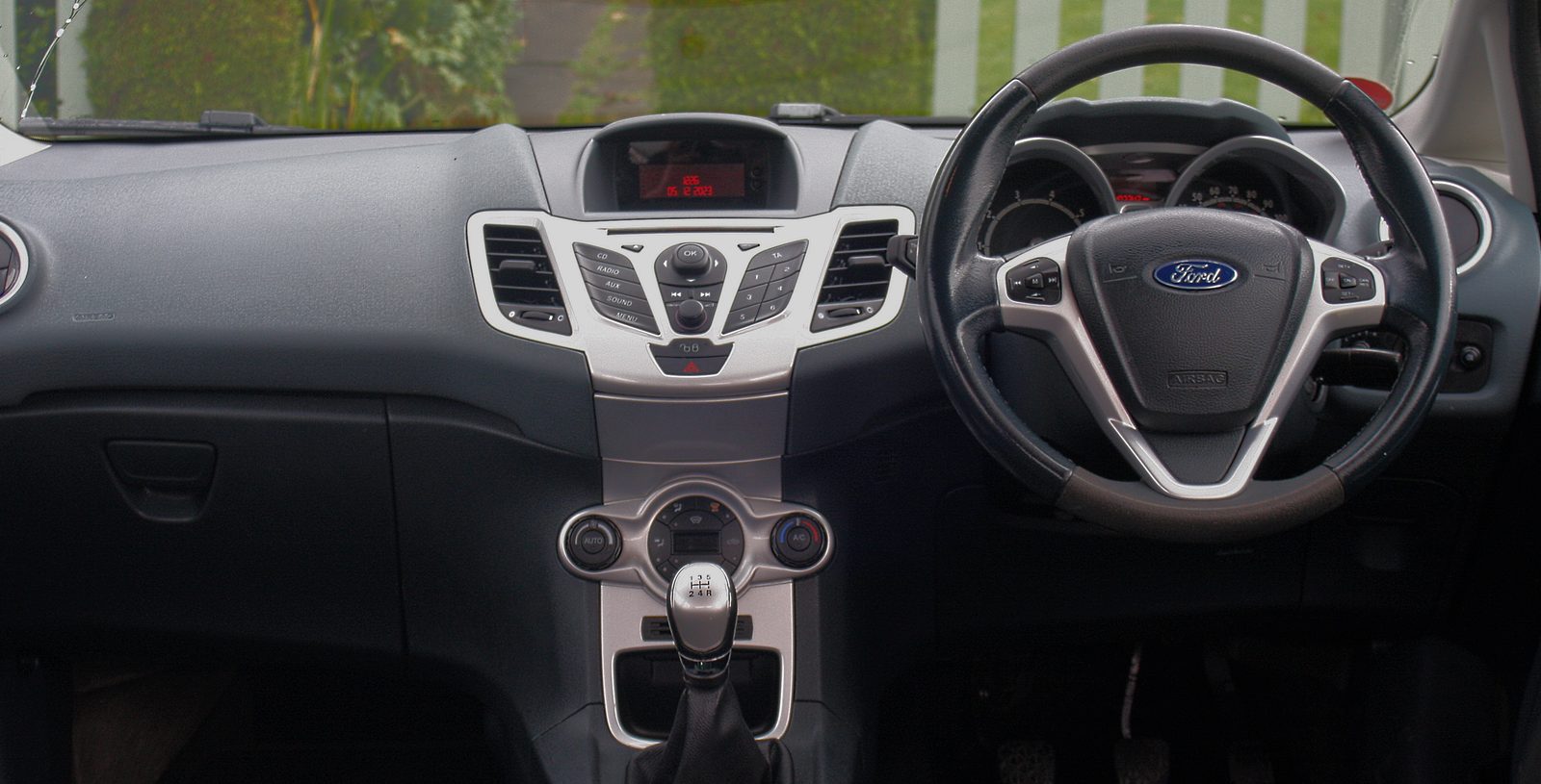Dashboard of a right-hand-drive 2009 Ford Fiesta Titanium (Mk7): instrument cluster behind the steering wheel with its red centre display, and the silver centre stack
